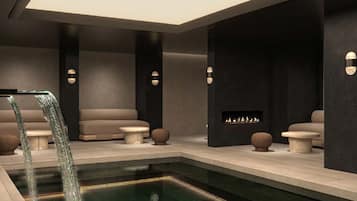 Un área de spa moderna con piscina, asientos y chimenea.