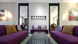 Un salon moderne avec deux canapés violets, une table basse centrale et un élément décoratif mural.