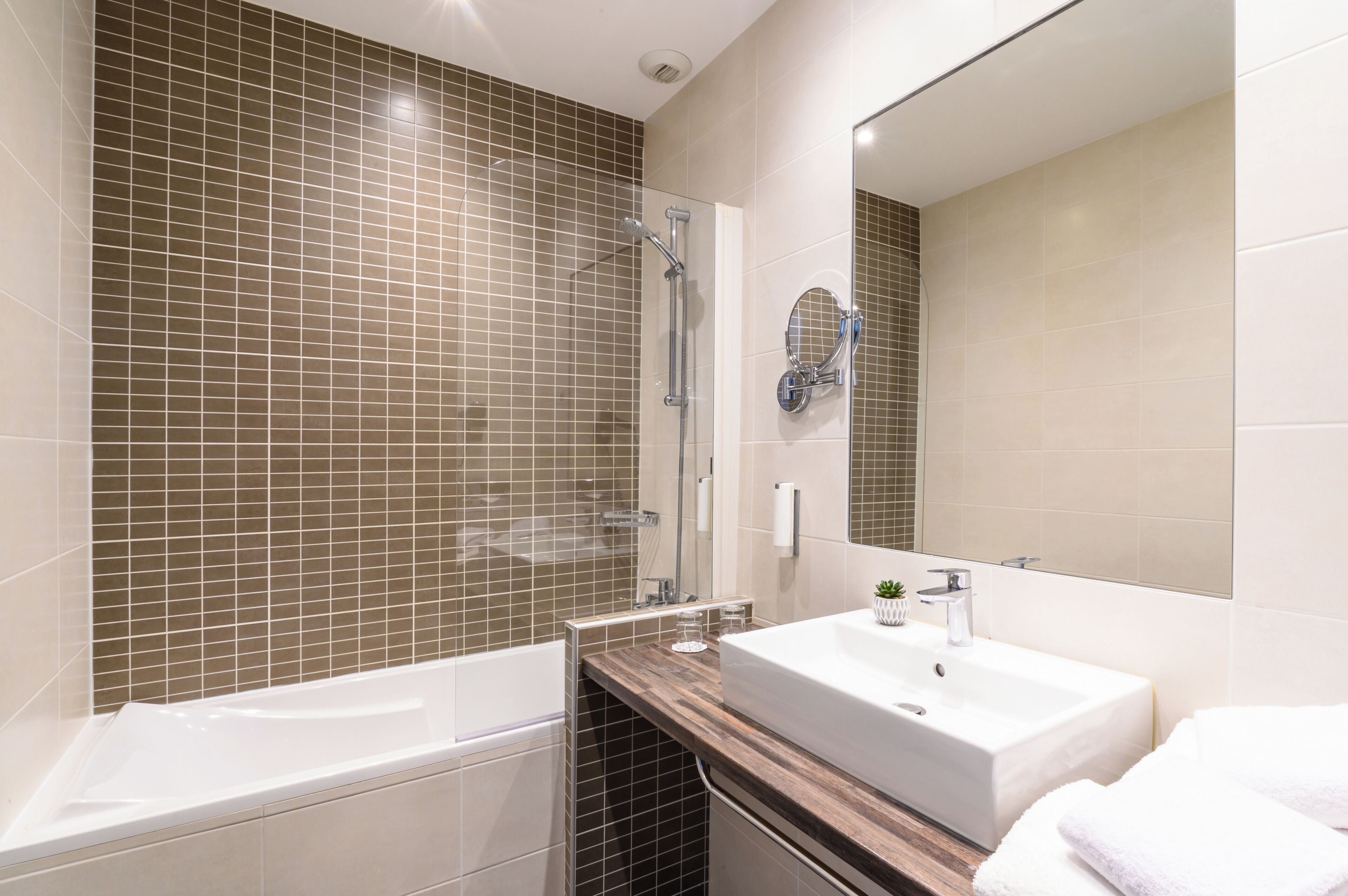 A modern bathroom with a bathtub, a sink, and a large mirror.