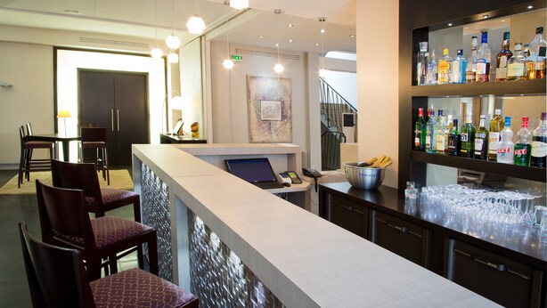 Un espace bar avec un comptoir, des sièges et un assortiment de bouteilles.