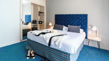 A modern hotel room with a large bed, a wardrobe, a desk, and a bathroom.
