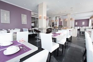 Enjoy meals in a stylish dining area with white tables, decorative panels, and pendant lighting.
