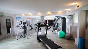 Une salle de sport équipée de tapis de course, de ballons d’exercice et d’appareils de musculation.