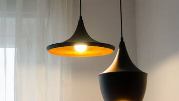 Two pendant lights hanging from the ceiling in a room with a sheer curtain and a light-colored wall.