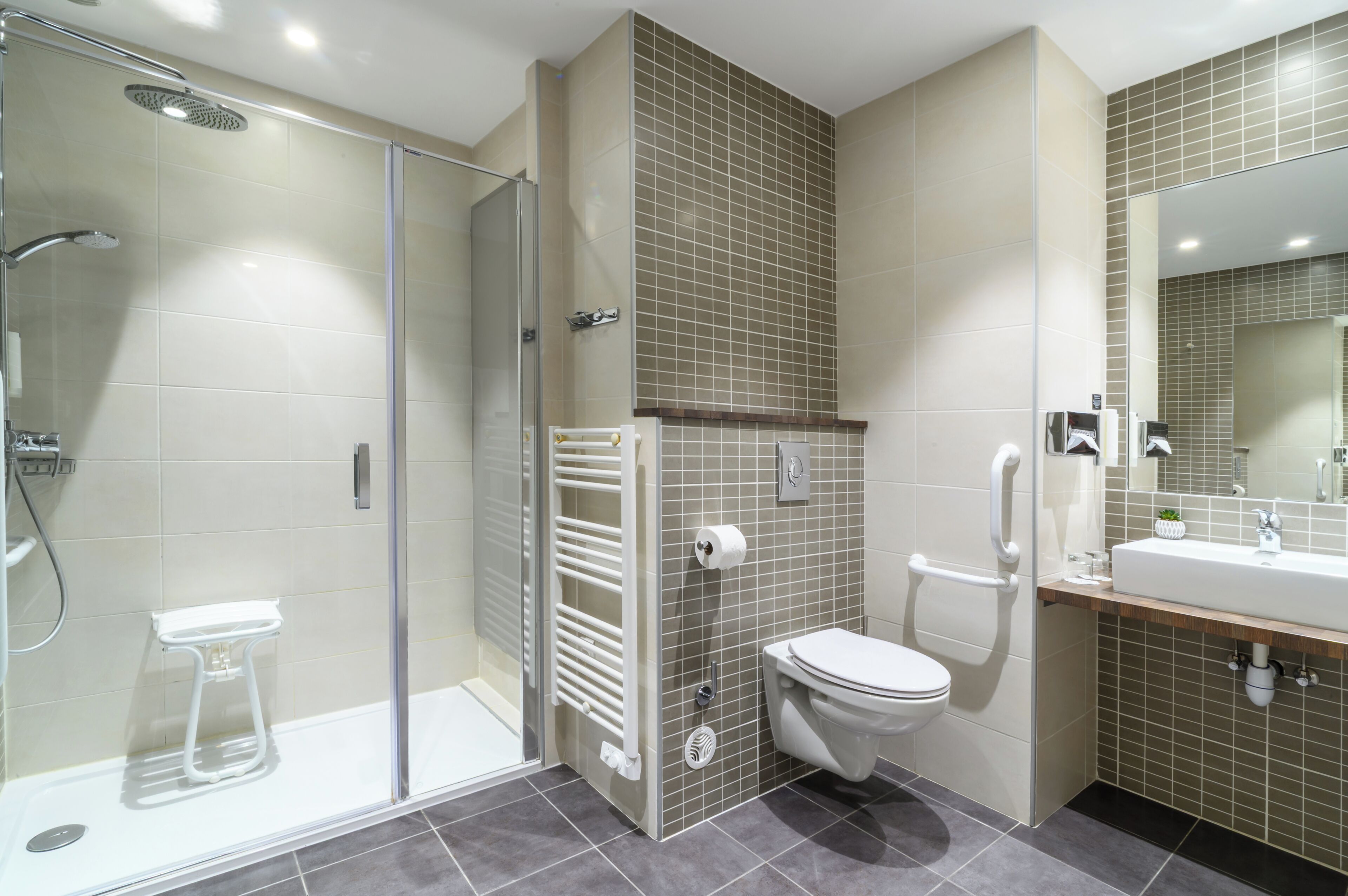 A modern bathroom with a glass-enclosed shower, a toilet, and a sink with a mirror.