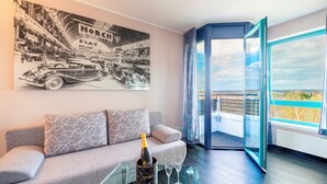 Ein modernes Wohnzimmer mit grauem Sofa, einer Champagnerflasche und einem großen Fenster mit Aussicht.