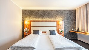Ein Doppelbett mit weißen Leinen, zwei Nachttische mit Lampen, eine Steinsäule und ein Holz-Kopfteil.