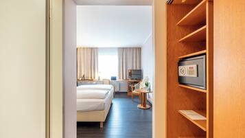 A hotel room with a bed, a desk, a TV, and a wooden shelf.