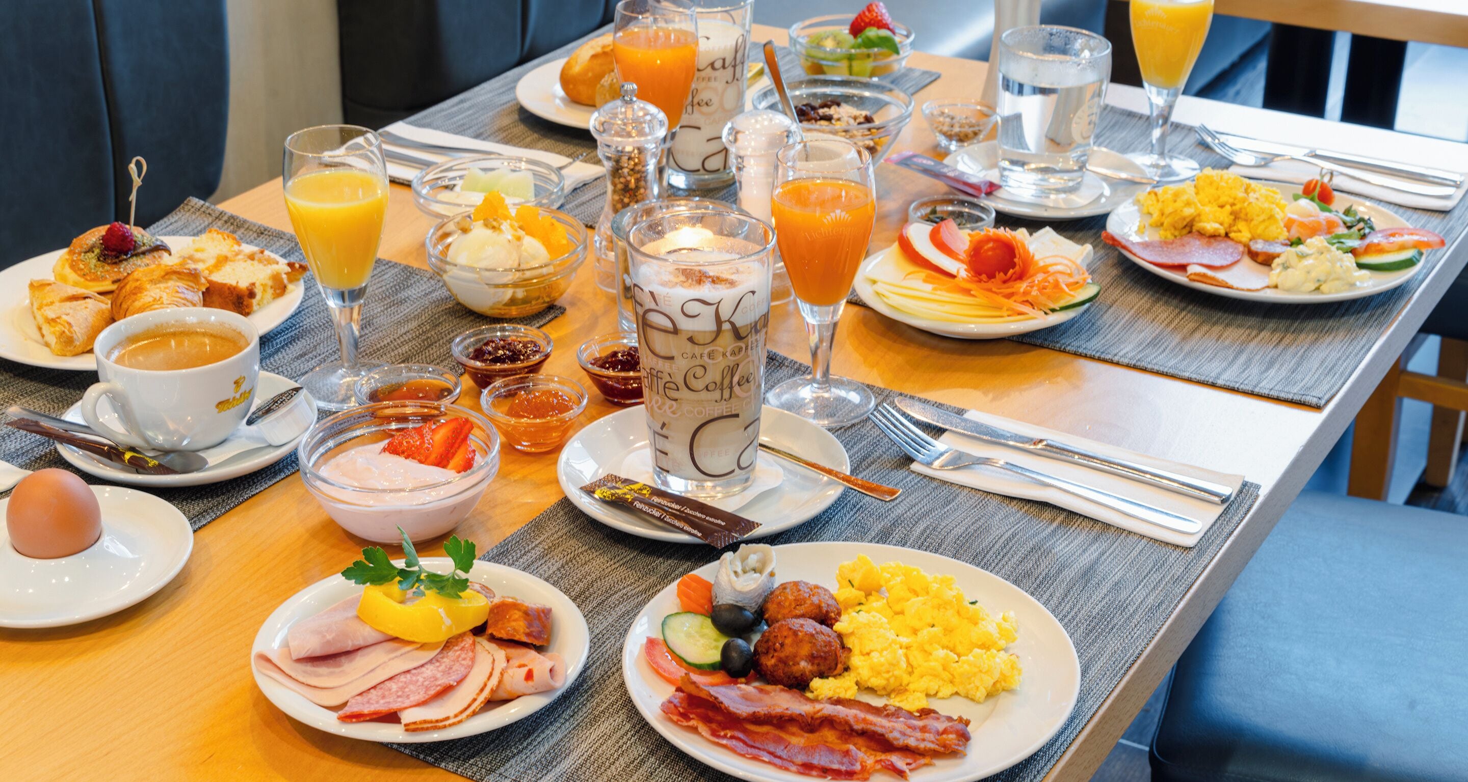 A breakfast buffet with various dishes, drinks, and utensils.