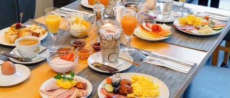 A breakfast buffet with various dishes, drinks, and utensils.