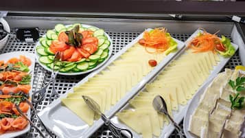 A buffet with various food items including sliced cucumbers, tomatoes, and cheese.
