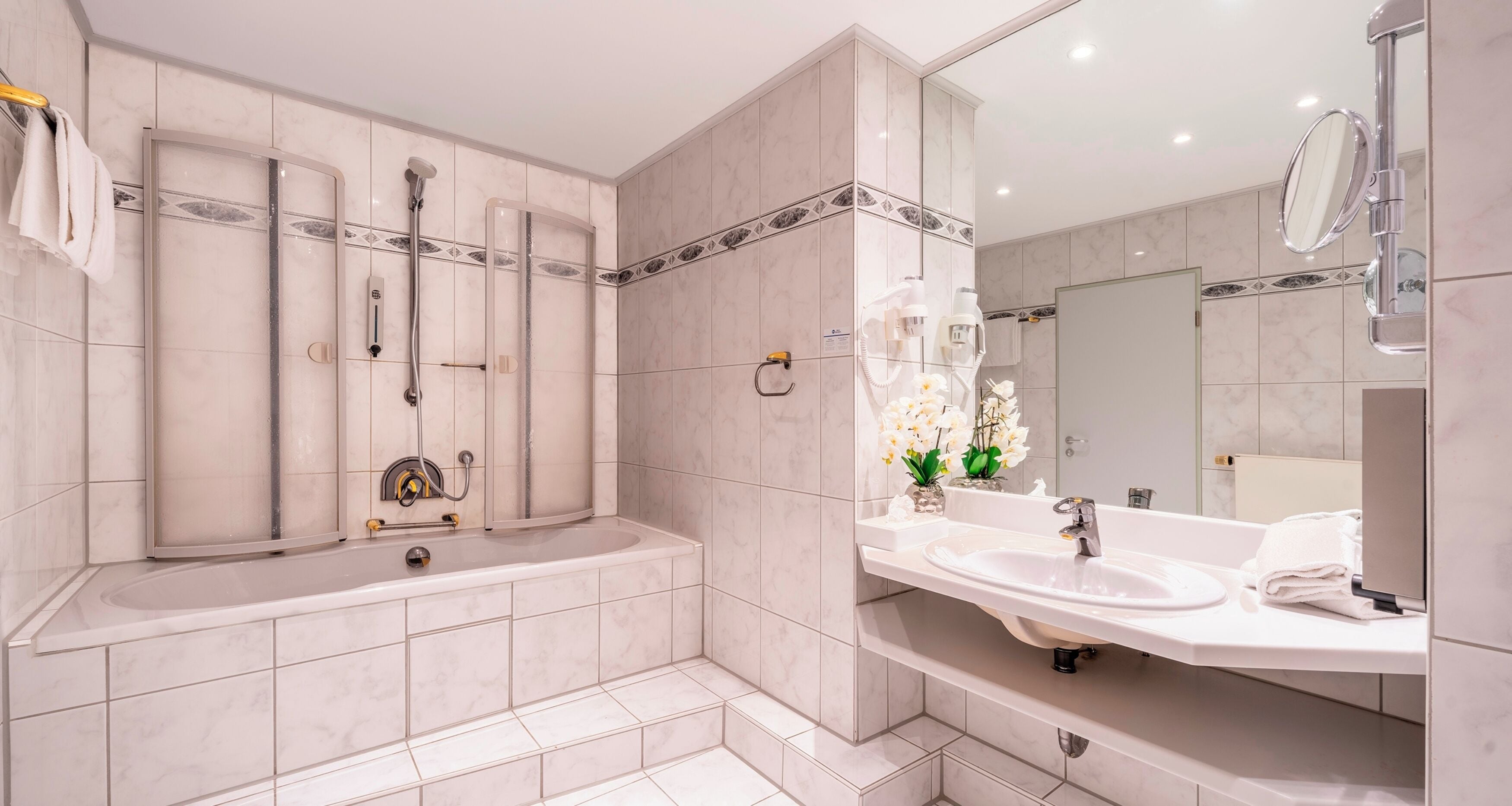 A modern bathroom with a bathtub, shower, and vanity with a sink and mirror.