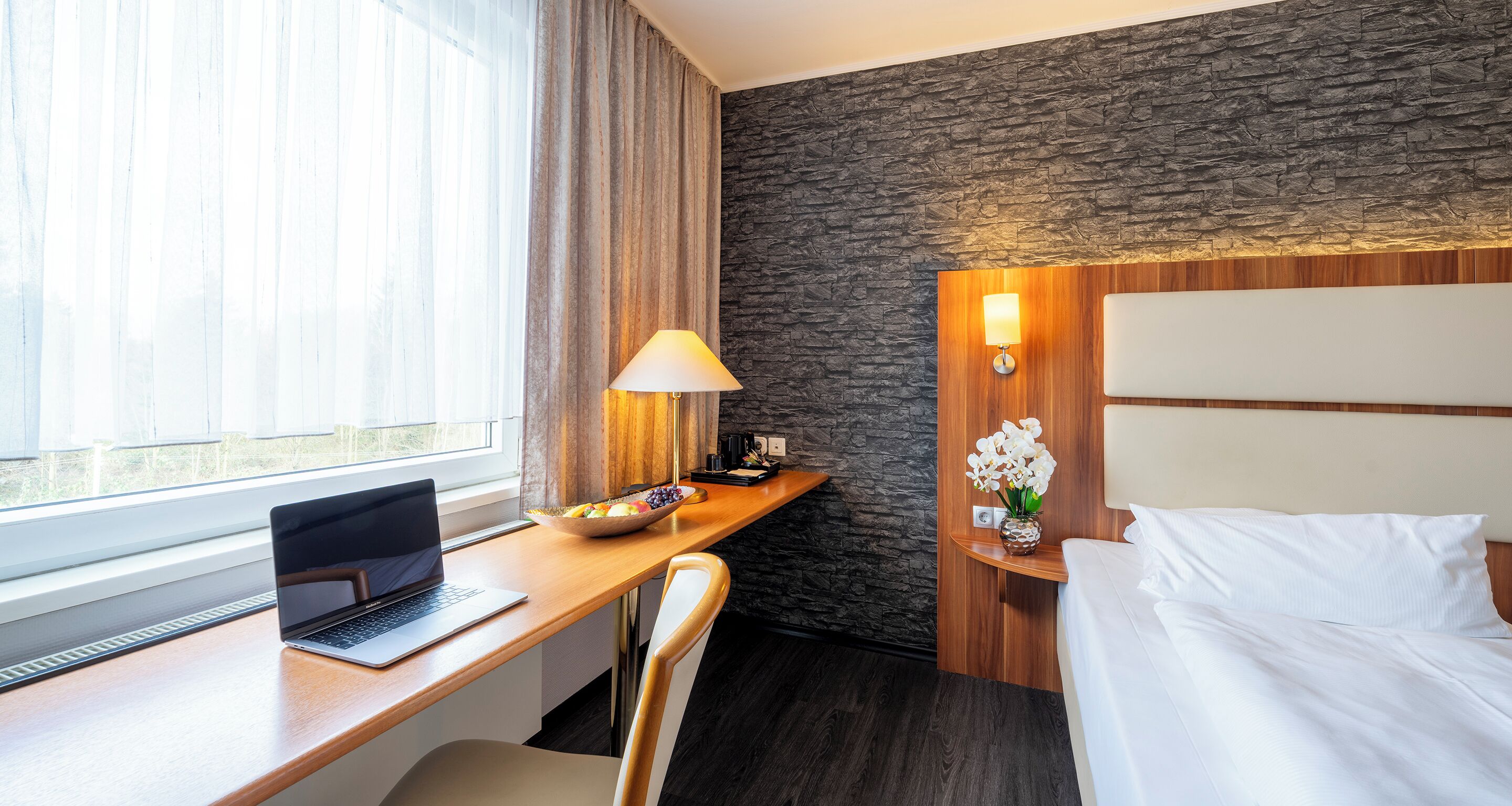 Une chambre d’hôtel équipée d’un bureau, d’un ordinateur portable et d’un lit.