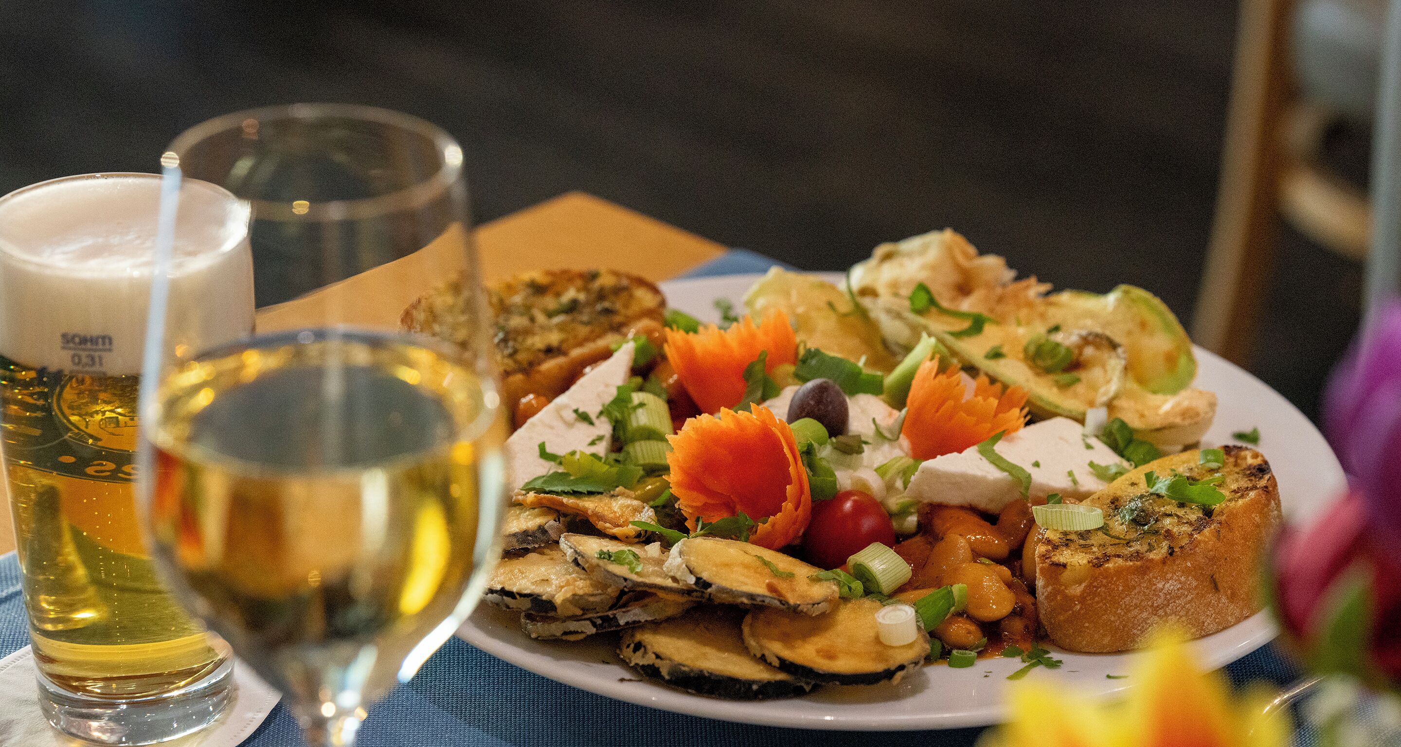 A plate of food with various toppings and a glass of white wine.