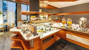 A modern breakfast bar with a variety of food and drink options, including fruits, cereals, and coffee machines.