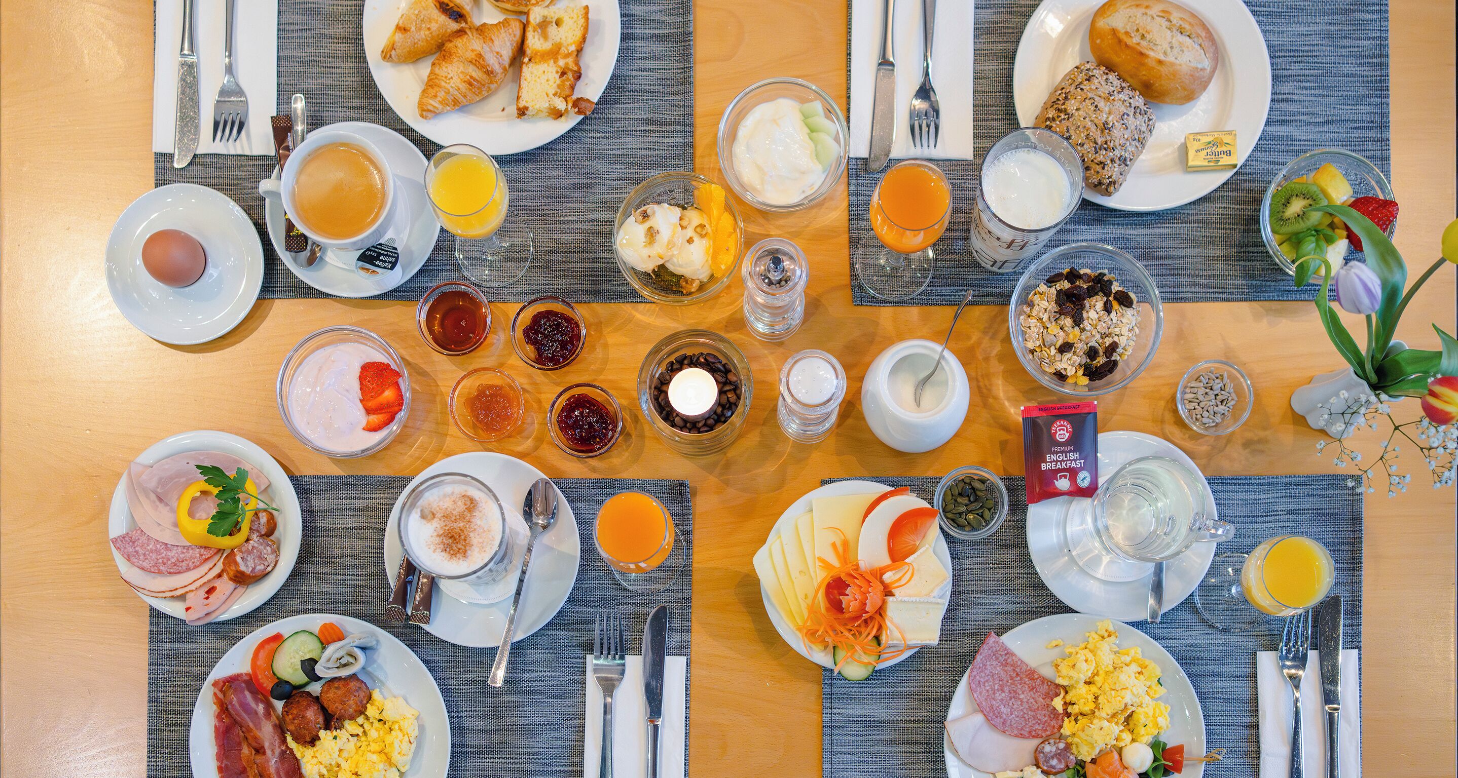 A breakfast buffet with various dishes, drinks, and condiments.