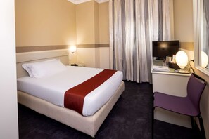 A hotel room with a bed, a desk with a computer, a chair, a TV, and a window with curtains. - Best Western Hotel Major (Milan)