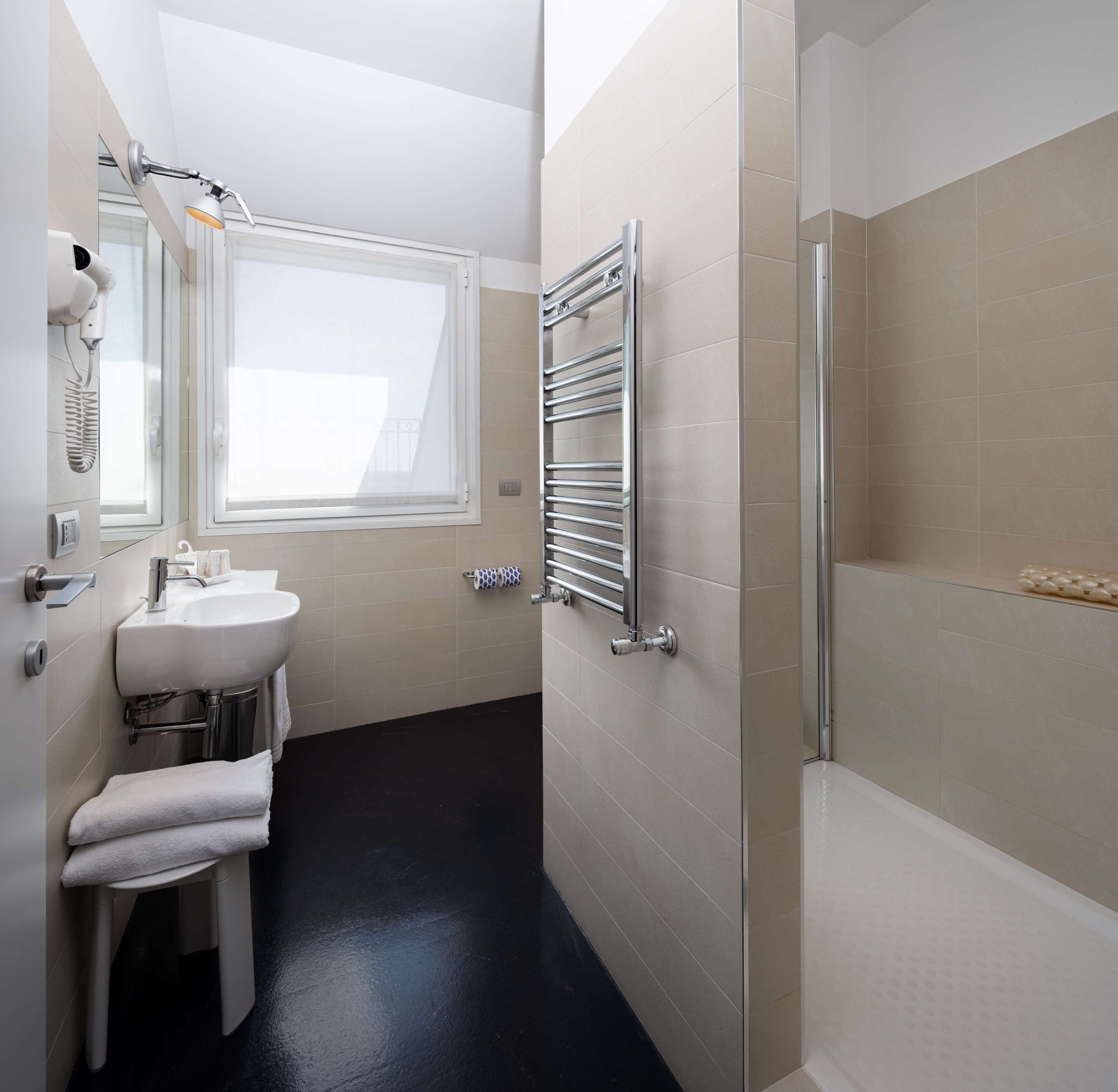 Une salle de bain moderne équipée d’un lavabo, d’un miroir, d’un porte-serviettes et d’un espace douche.