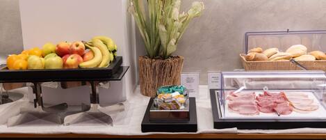 A buffet with fruits, bread, and deli items.