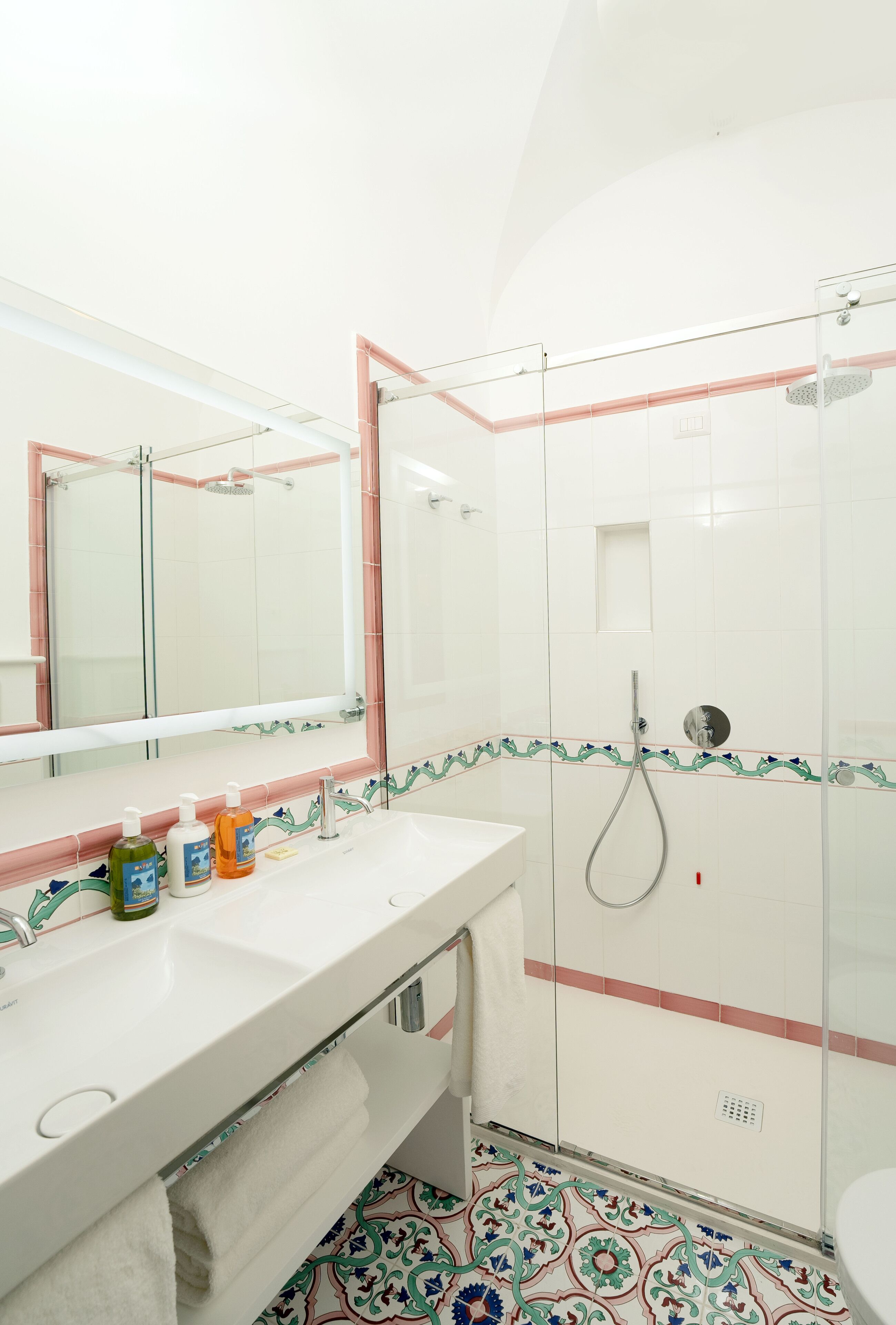 Un baño con lavamanos, espejo y ducha blancos.