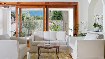 Uma sala de estar moderna com um sofá bege, uma mesa de centro de madeira e uma parede de pedra.