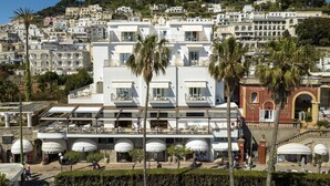 A hotel with multiple floors, outdoor seating areas, and a view of a hillside.