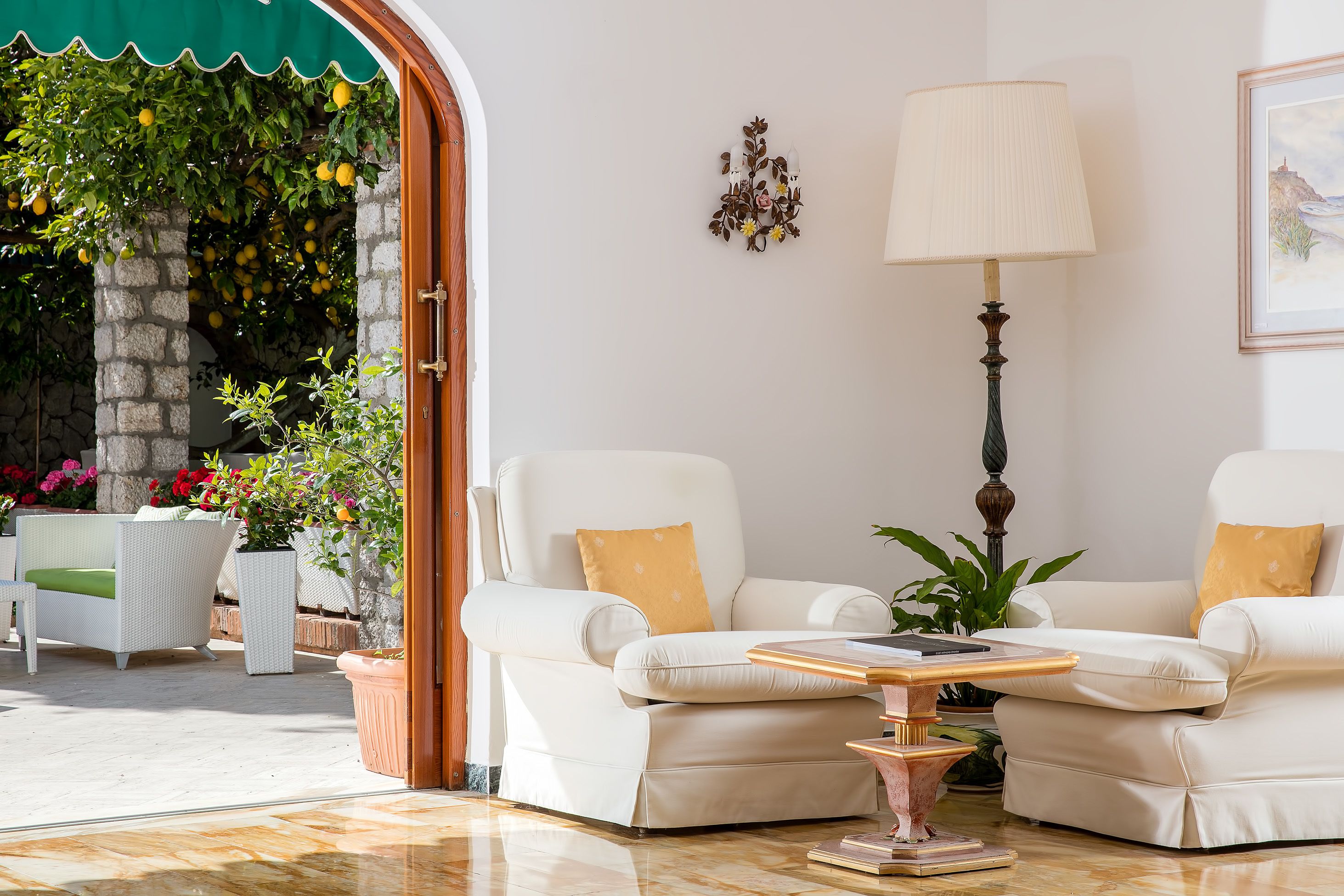 A well-lit indoor seating area with two white sofas, a table, and a lamp.