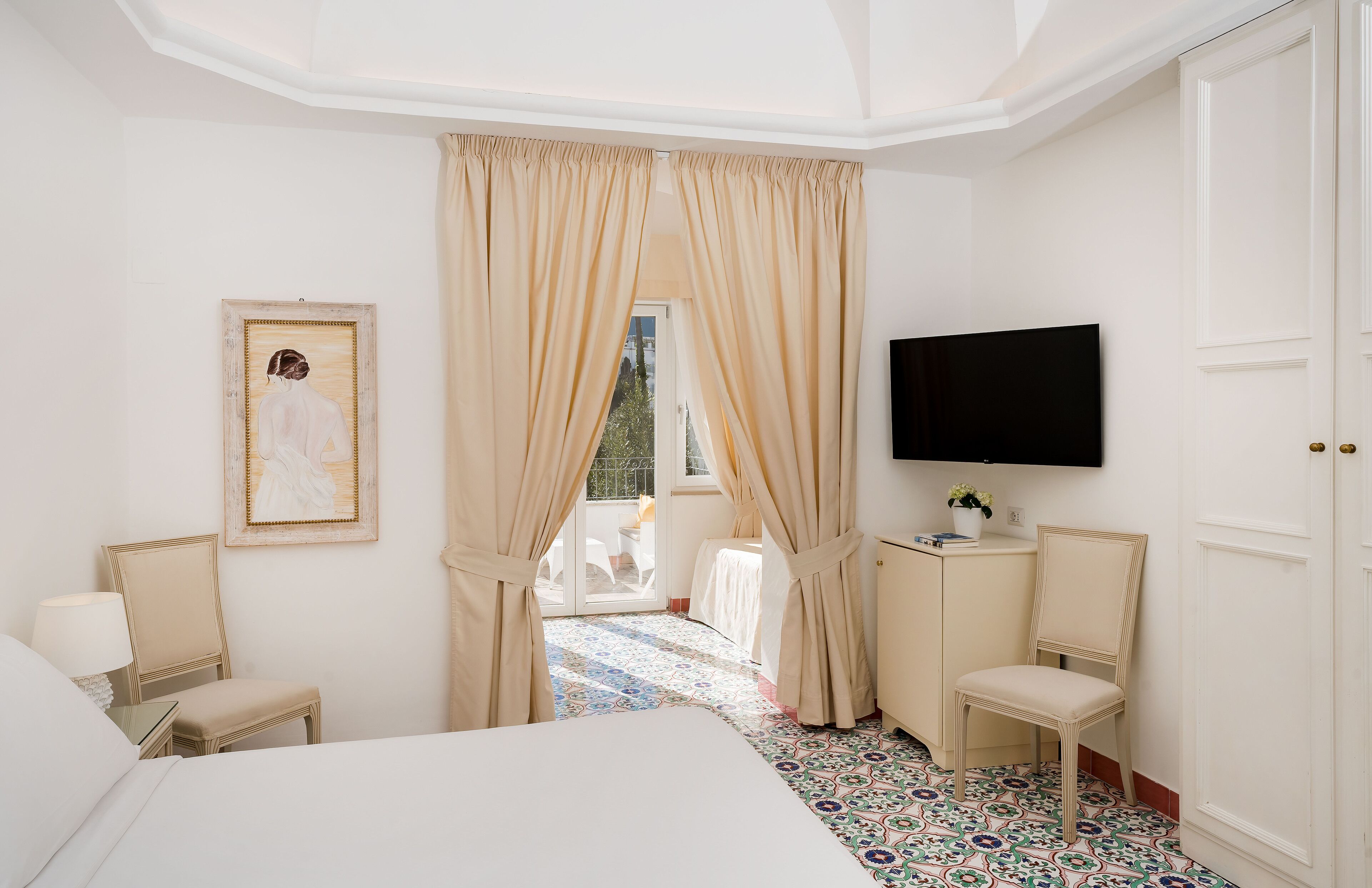Habitación de hotel con cama, escritorio, silla, televisor y un cuadro en la pared.