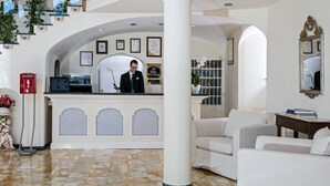 A lobby with a reception desk, a staircase, and a seating area.