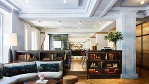A spacious library with a sofa, ottomans, and bookshelves. - Hotel Revival Baltimore (Baltimore)