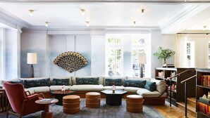 A spacious living room with a sectional sofa, a red armchair, a coffee table, and a bookshelf. - Hotel Revival Baltimore (Baltimore)