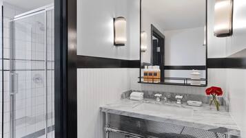 Un baño moderno con cabina de ducha de vidrio, lavamanos de mármol y un espejo grande con apliques de pared.