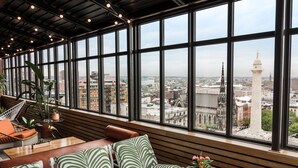 A modern interior with large windows, wooden slats, and green-striped seating. - Hotel Revival Baltimore (Baltimore)