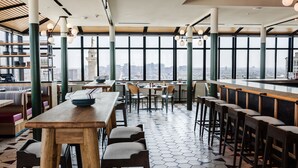 A modern restaurant with high ceilings, large windows, and a city view. - Hotel Revival Baltimore (Baltimore)