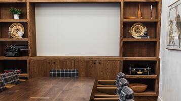 A conference room with a long wooden table, six upholstered chairs, and wooden shelving with various decorative items.