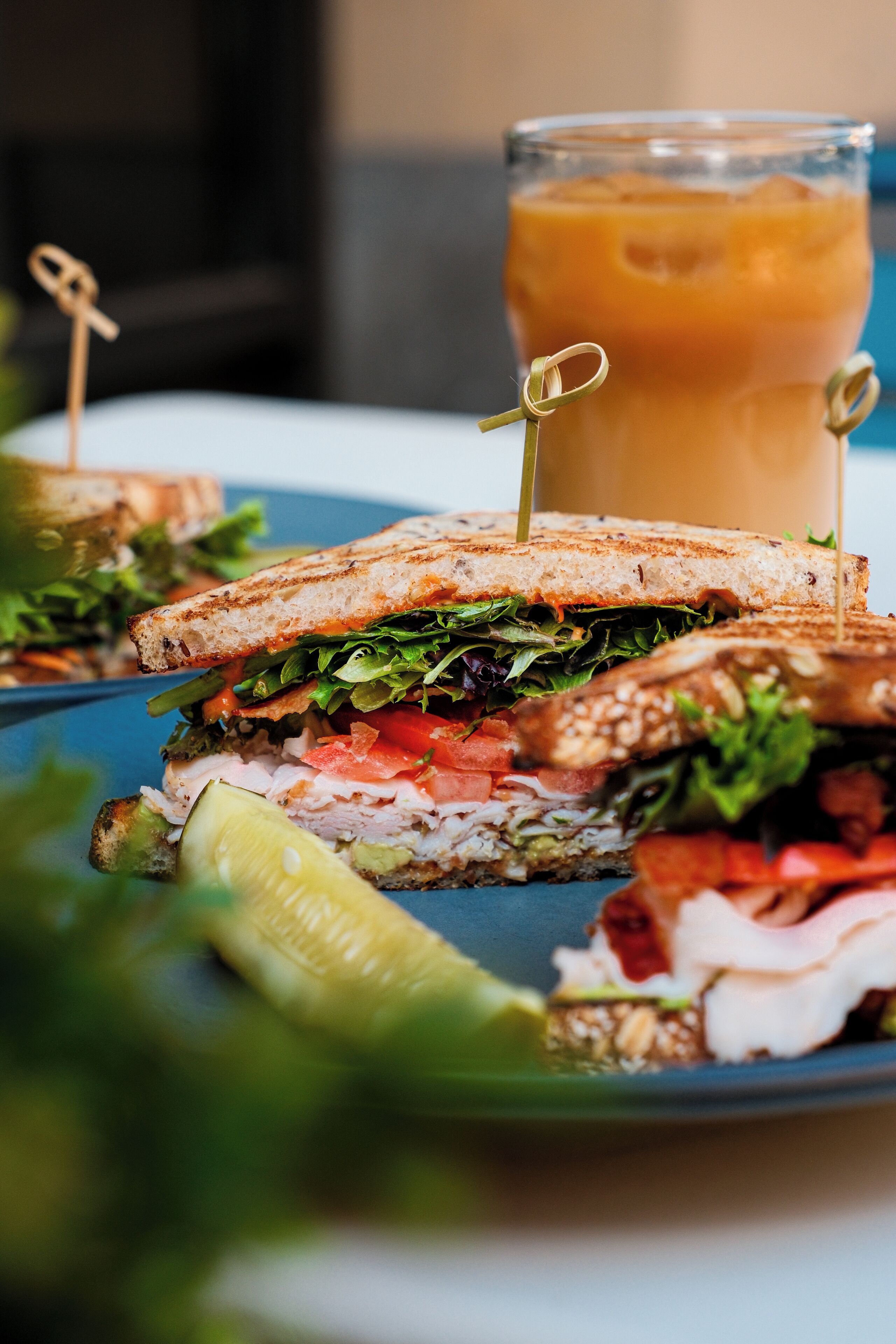 A sandwich with a drink in the background.