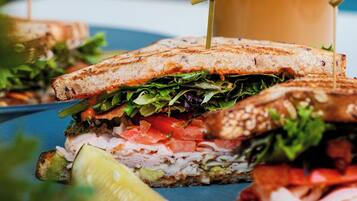 A sandwich with a drink in the background.