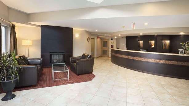 A hotel lobby with a reception desk, seating area, and a fireplace.