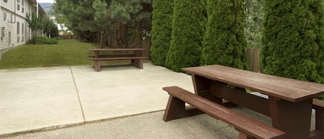 A picnic table and bench in a courtyard with a building in the background.