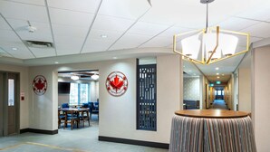 A hotel lobby with a round table, a large decorative wall piece, and a long corridor leading to the exit. - Comfort Inn Sarnia (Sarnia)