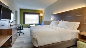 Een hotelkamer met een groot bed, een bureau met stoel, een televisie en een raam met natuurlijk licht.