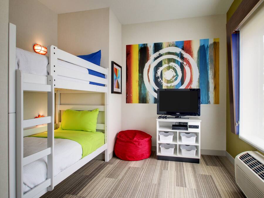 A room with bunk beds, a red bean bag, a TV, and a colorful abstract painting.