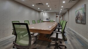 Een vergaderruimte met een lange tafel, groene netstoelen en een vloerbedekking.