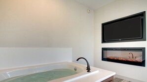 Een moderne badkamer met een vrijstaand bad, een aan de muur bevestigde televisie en een ingebouwde open haard.