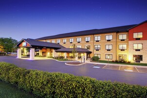 A multi-story hotel with a parking lot and a landscaped area.