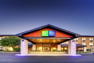 A Holiday Inn Express & Suites building with a prominent sign, a brick facade, and a well-lit entrance.