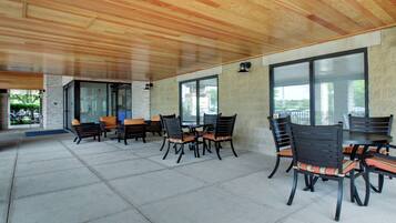 Un espacio de patio exterior con techo de madera, paredes de piedra y ventanas amplias.