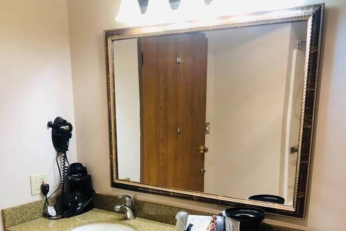 Un baño con lavamanos, espejo y secador de pelo.