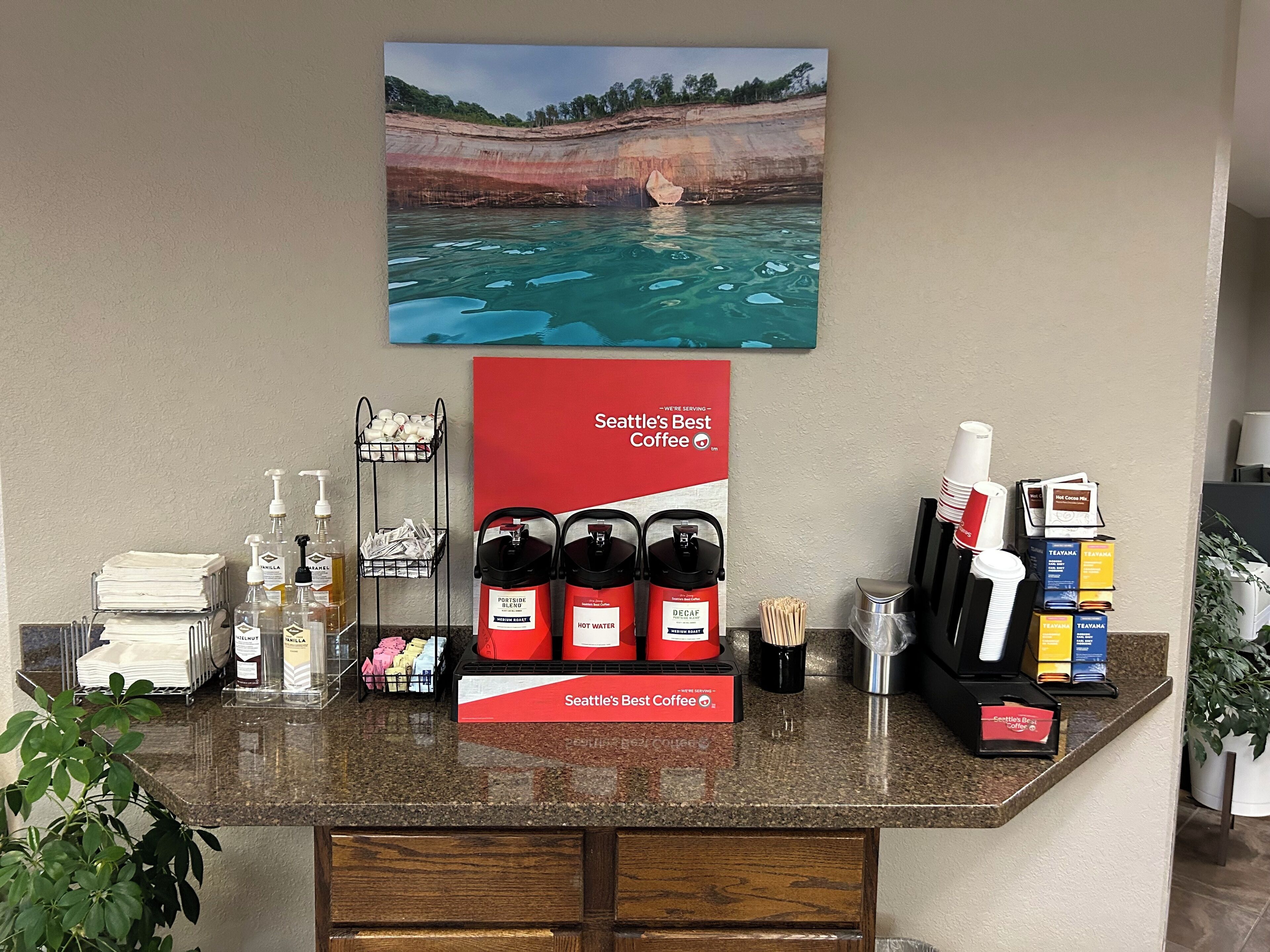A coffee station with a sign reading "Seattle's Best Coffee" and a scenic painting above it.