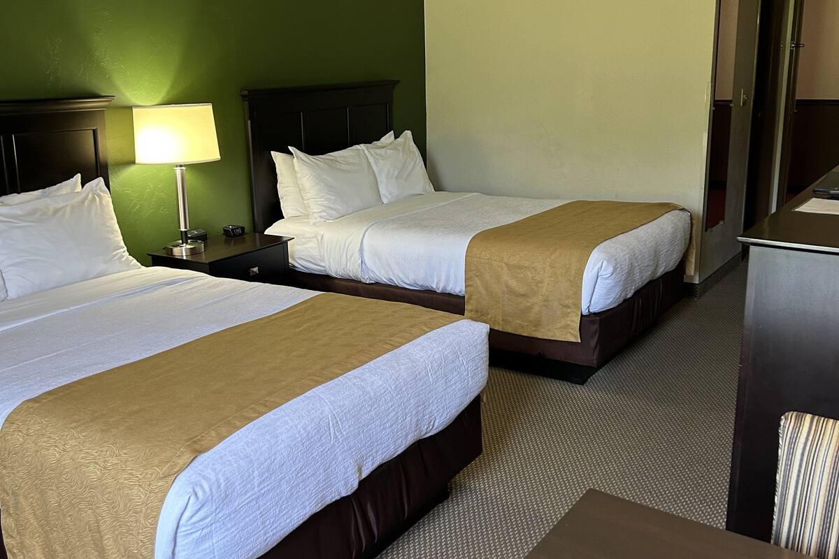 Una habitación de hotel con dos camas, un escritorio y una lámpara.